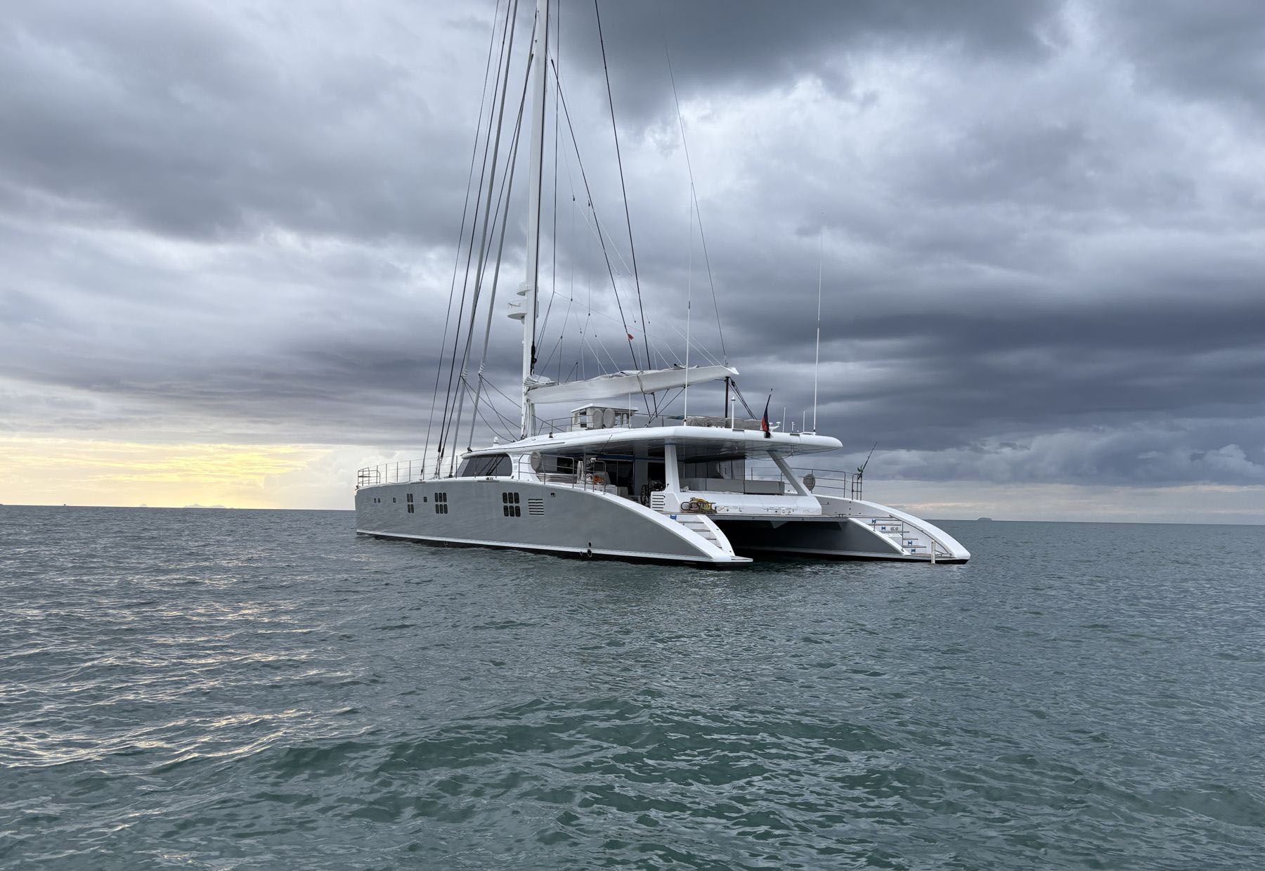 The catamaran SV Che at anchor under a darkening storm sky