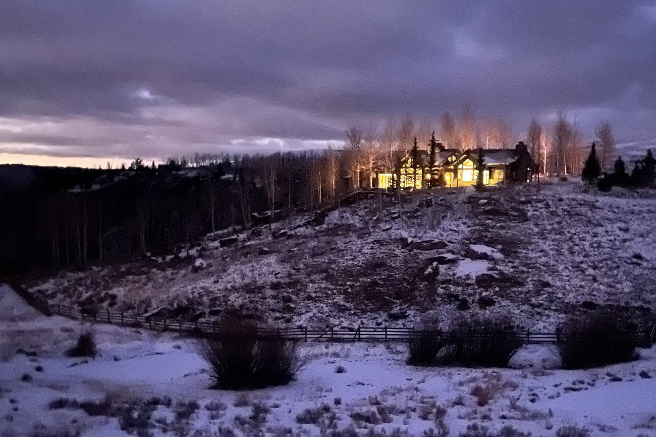 A mountain home lit at dusk in remote snow country